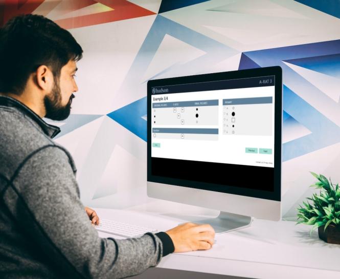 Man looking at a computer screen that contains an example question from an abstract reasoning test.